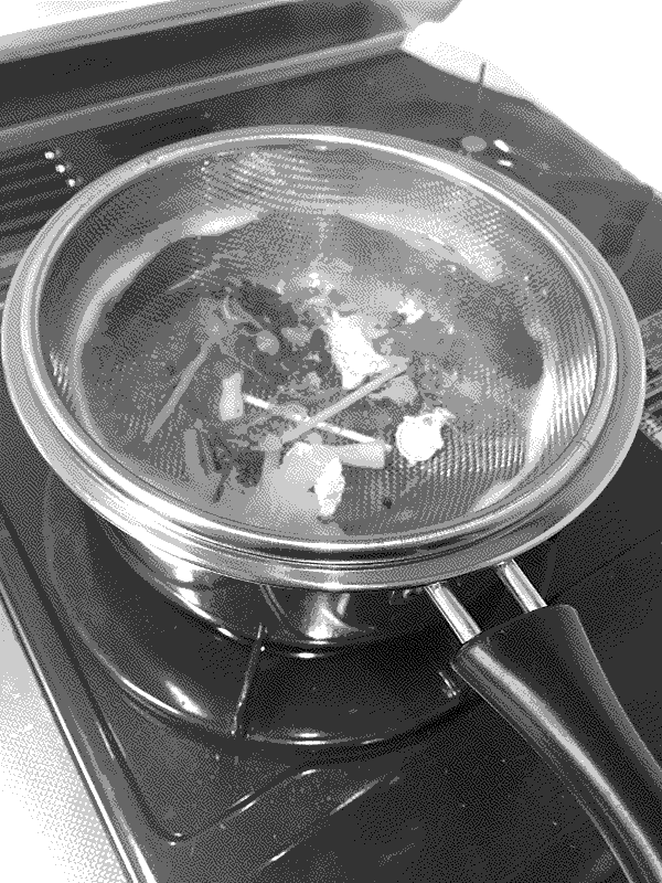 Photo of pieces of the Doppenganger figure being boiled through a sieve.