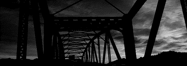 A photo of a bridge at sunset, orange clouds against a darkening sky.